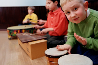 Group of students (8-10) playing musical instruments in classroom